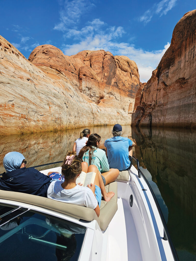 People sitting in the bow of a boat in a desert canyon