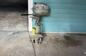 Vintage Johnson Outboard Motor leaning against a garage wall