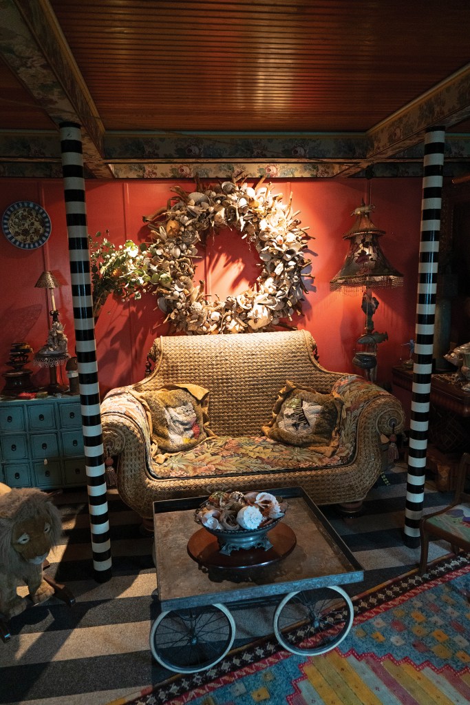 Luxurious vintage wooden yacht cabin interior showcasing polished mahogany bulkheads, a plush white upholstered corner sofa, an art deco lampshade, and a companionway ladder leading up to the deck.