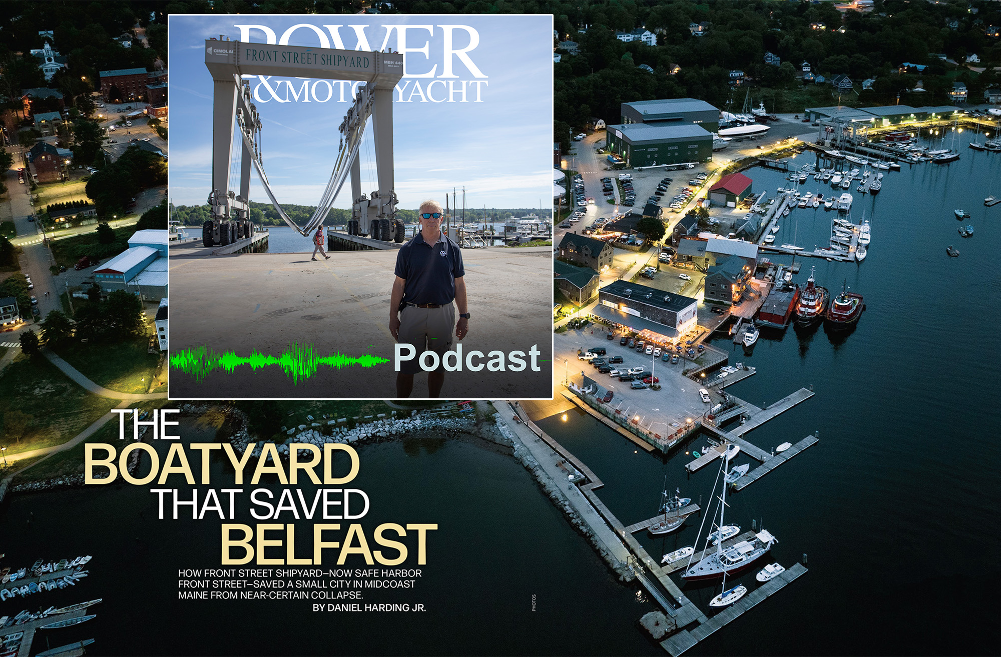 An aerial, high-angle twilight view of a bustling waterfront shipyard and marina with a prominent article title overlay reading "THE BOATYARD THAT SAVED BELFAST." In the top left corner, a rectangular inset displays a Power & Motoryacht podcast graphic showing a man standing in front of a massive "FRONT STREET SHIPYARD" mobile boat hoist, complete with a green audio waveform and the word "Podcast." The background shows the illuminated Safe Harbor Front Street Shipyard facility in Belfast, Maine, with docks, service buildings, and boats floating in the calm water.