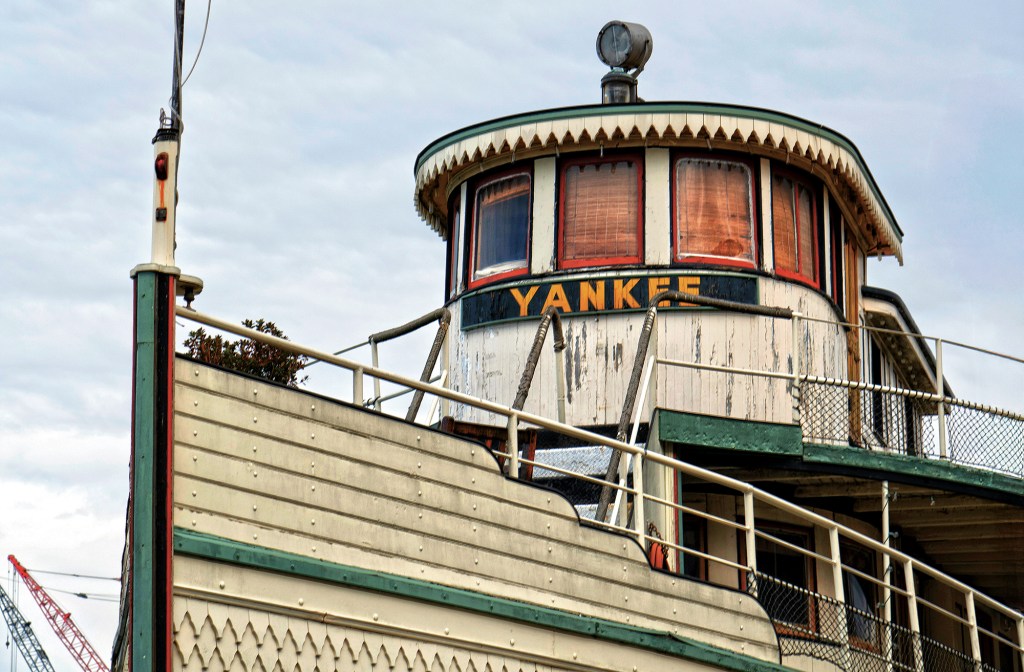 feat_Yankee A classic wooden commuter yacht with polished timber decks and white trim cruising smoothly at speed on bright water.