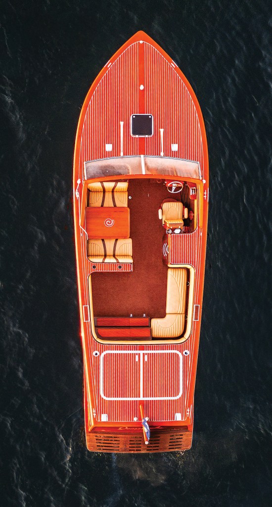 A top-down aerial view of a classic mahogany wooden boat showing its deck layout, cockpit seating, and rear swim platform.