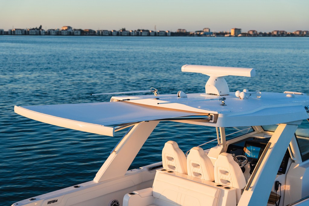 The fiberglass hardtop and helm area of an Intrepid 35 Valor boat at sunset, featuring an extended retractable aft sunshade, radar dome, and three custom helm chairs.