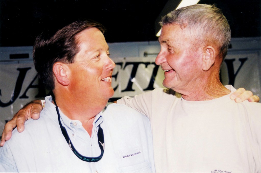 Jarrett Bay founder Randy Ramsey smiling and embracing early benefactor Omie Tillett in a candid moment in front of a Jarrett Bay banner.