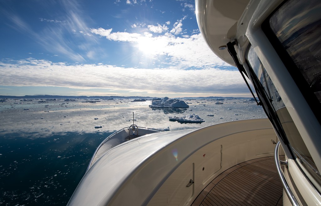 View from the Portuguese bridge of the yacht Beothuk looking out over ice-choked blue waters under a bright, sunny sky.