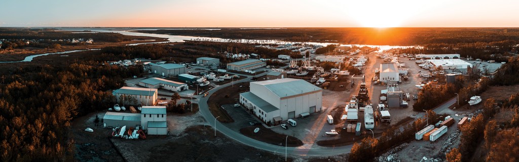 An expansive panoramic aerial view of the Jarrett Bay Boatworks facility and industrial park along the Intracoastal Waterway at sunset.