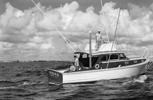 A vintage black-and-white photograph of the sportfishing boat Marlin II out of Freeport, New York, cruising off Fort Lauderdale with three crew members on board, including a captain perched on the open flying bridge with canvas dodger.