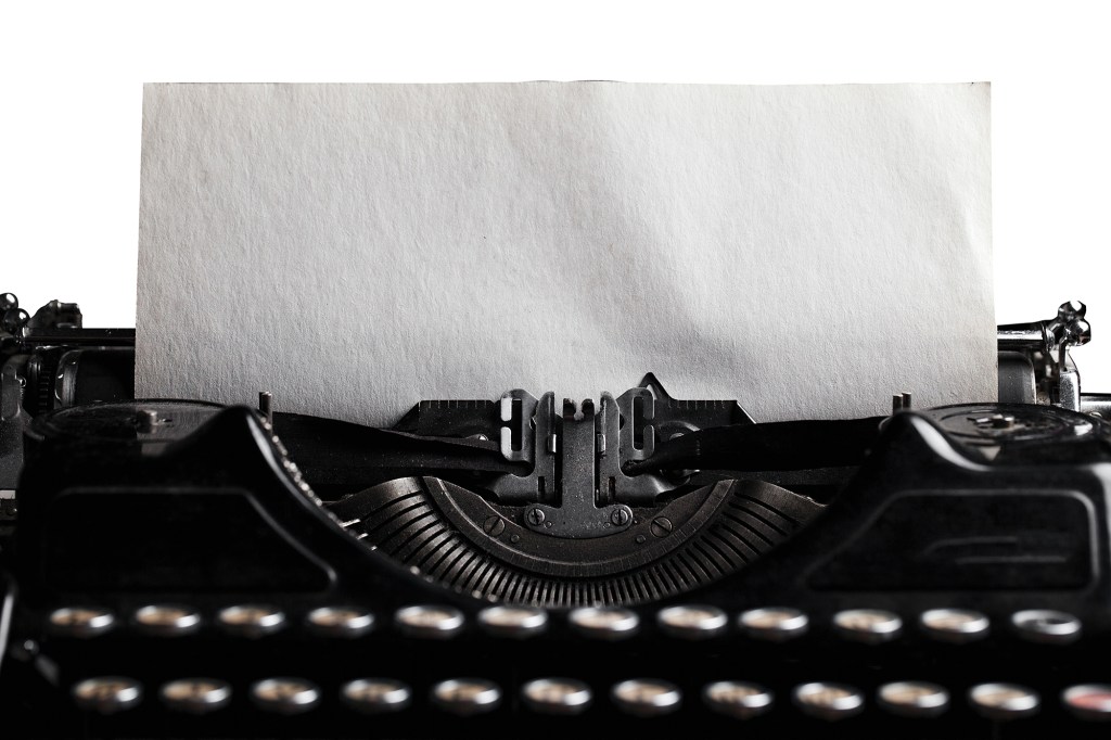 old-fashioned typewriter with a blank paper sheet.