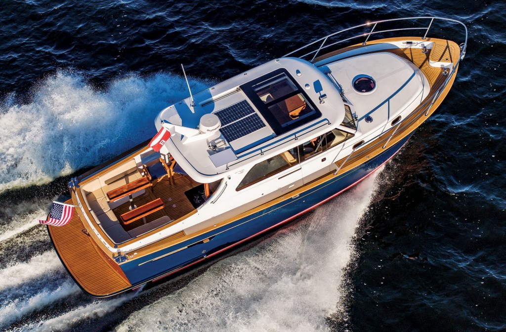 feat_Duchey35_Halsey_1003 An aerial overhead view of a blue and white Duchy 35 motor yacht underway, highlighting its teak swim platform, spacious aft cockpit seating, teak side decks, and roof-mounted solar panels.