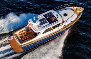 feat_Duchey35_Halsey_1003 An aerial overhead view of a blue and white Duchy 35 motor yacht underway, highlighting its teak swim platform, spacious aft cockpit seating, teak side decks, and roof-mounted solar panels.