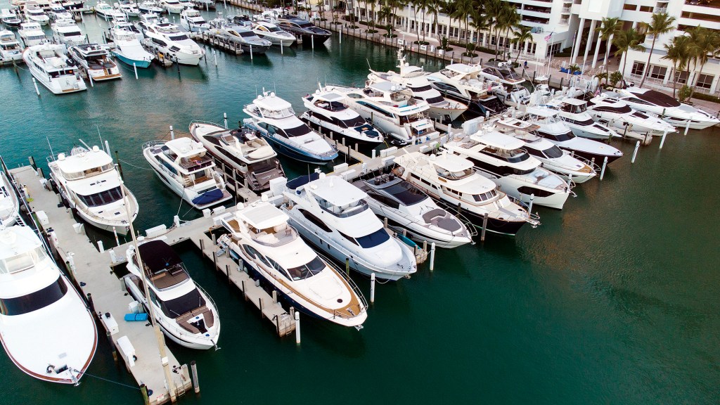 An aerial high-angle view of dozens of luxury yachts and motorboats docked side by side at a crowded marina.