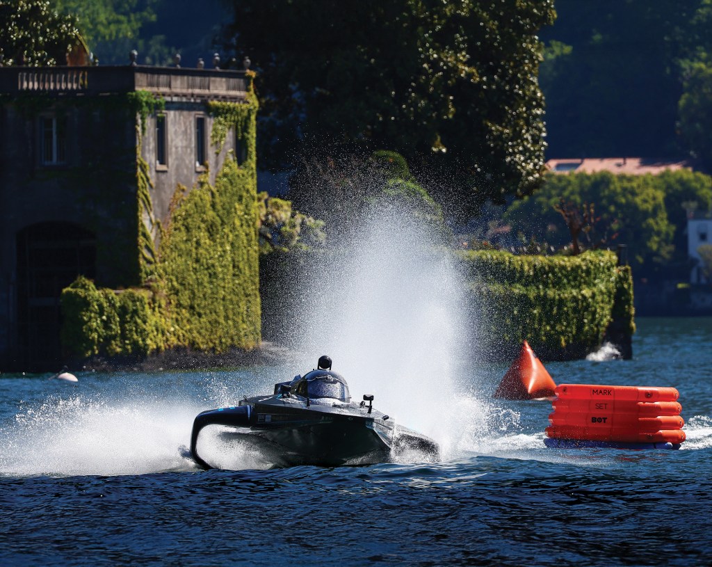 An all-electric RaceBird hydrofoil powerboat kicking up water spray near a turn buoy during an E1 race on Lake Como.