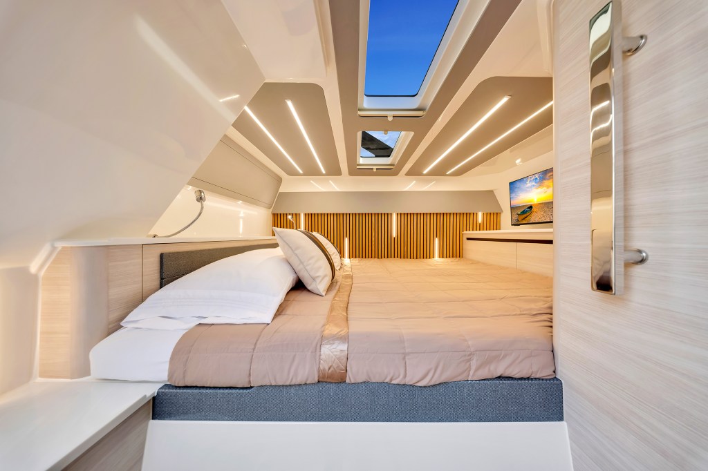 Modern master cabin stateroom below deck on an Aquila 45 Sport power catamaran, featuring a king-size bed, overhead skylights, ambient strip lighting, and contemporary wood paneling.