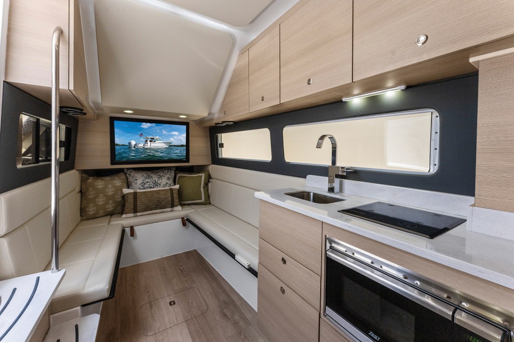 Interior cabin of the Scout 435 LXF featuring light wood cabinetry, kitchenette cooktop, sink, plush seating, and flat-screen TV.