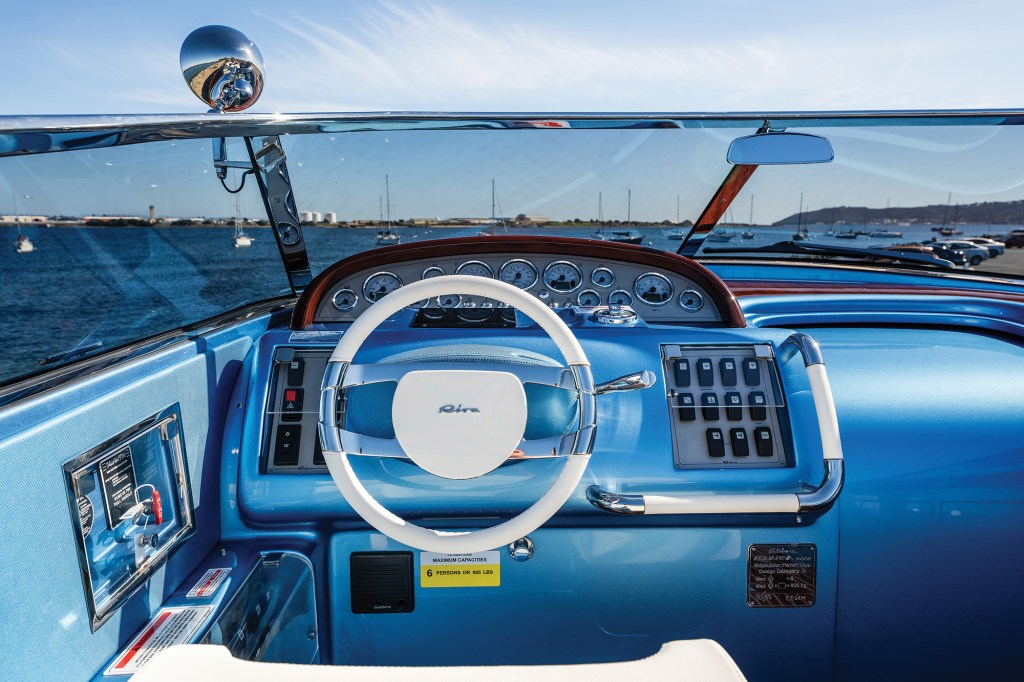 Helm station of a modern Riva Aquariva Special in Carta da Zucchero blue featuring retro analogue gauges and a white steering wheel.