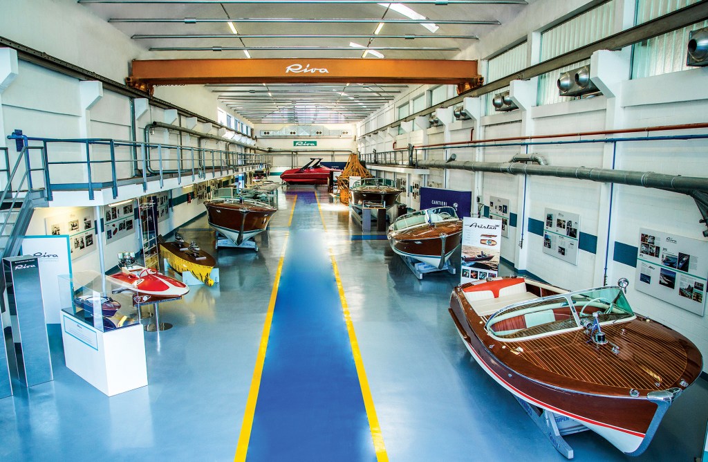 Historic wooden Riva motorboats and raceboats on display inside the RAM Riva Classiche museum showroom.