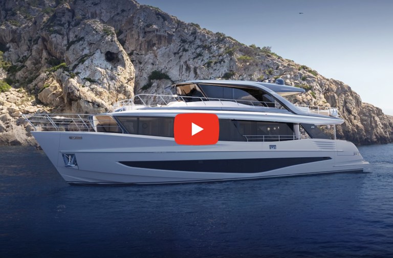 A white luxury motor yacht, the Princess X90, navigating calm blue water with a steep, rocky cliffside in the background under a clear sky. A red play button icon is overlaid in the center of the yacht.