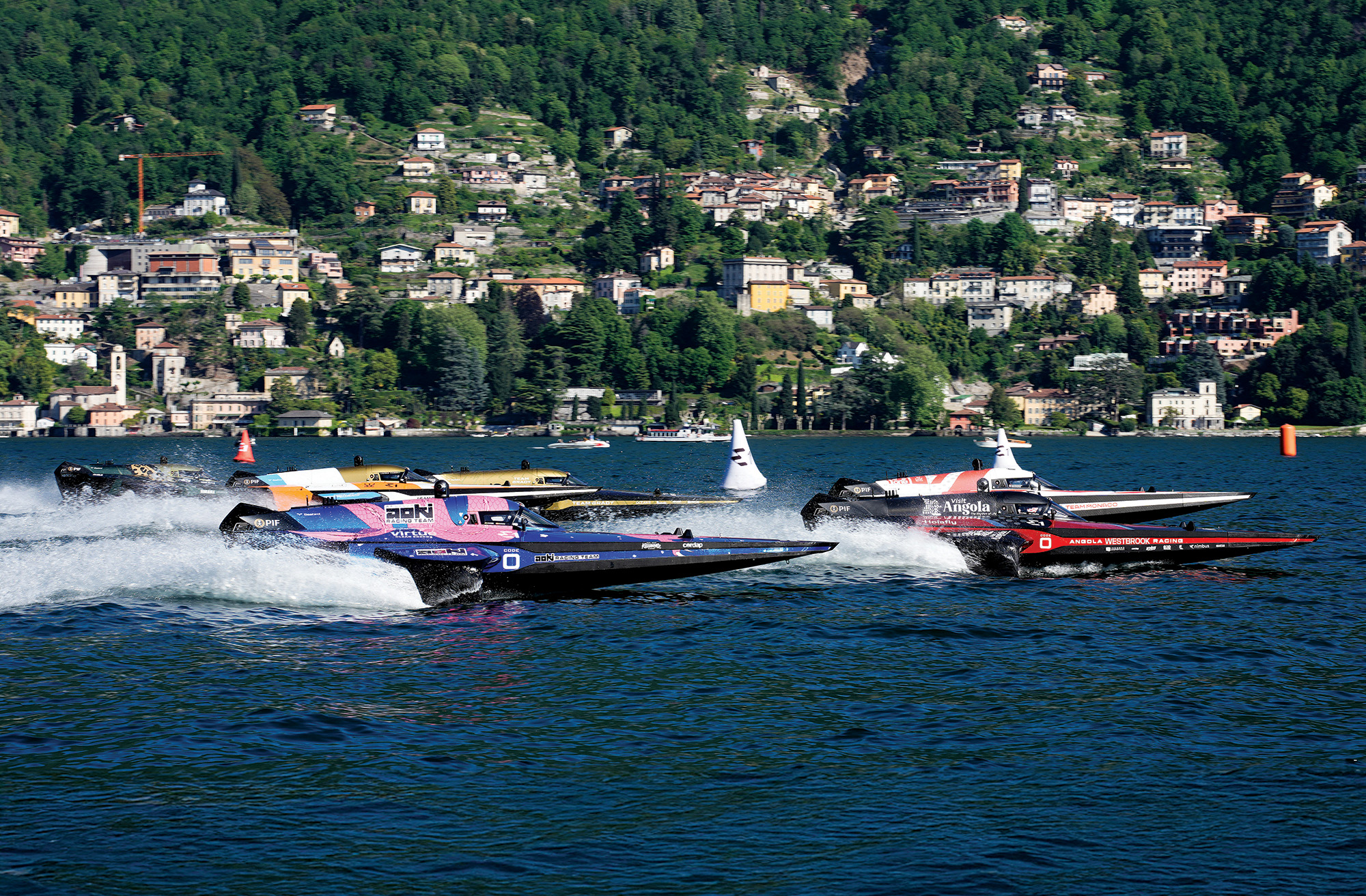 Electric RaceBird boats competing in the UIM E1 World Championship on Lake Como against a scenic hillside backdrop.