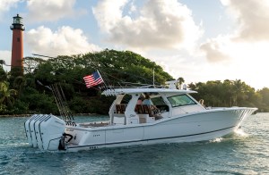 White Scout 435 LXF luxury center console boat with quad outboard Mercury engines cruising past Jupiter Inlet Lighthouse.