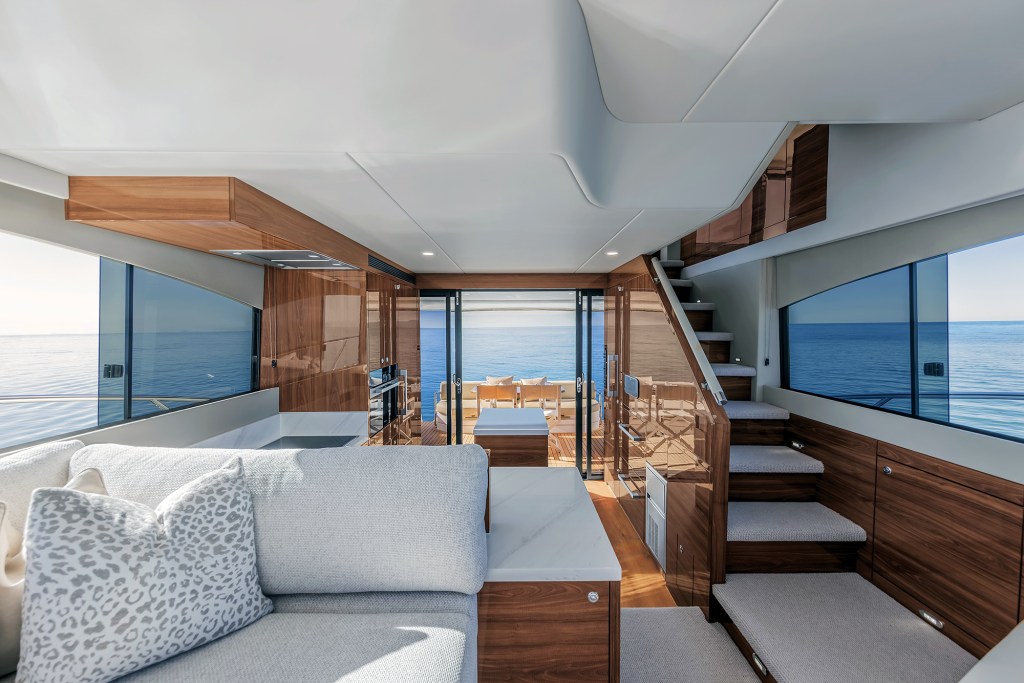 Interior view looking aft through the main salon and galley of a Maritimo M50 yacht toward sliding glass doors opening to the shaded cockpit deck.