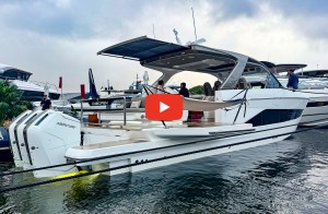 Docked Princess C48 Open day yacht equipped with triple white Mercury outboard motors, an extended aft sunshade awning, and a fold-down starboard terrace with a video play button overlay.