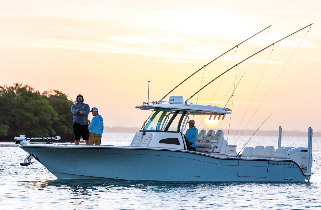 Side profile of a Grady-White 321 CE center console boat equipped with outriggers and dual Power-Poles on the water at sunset.