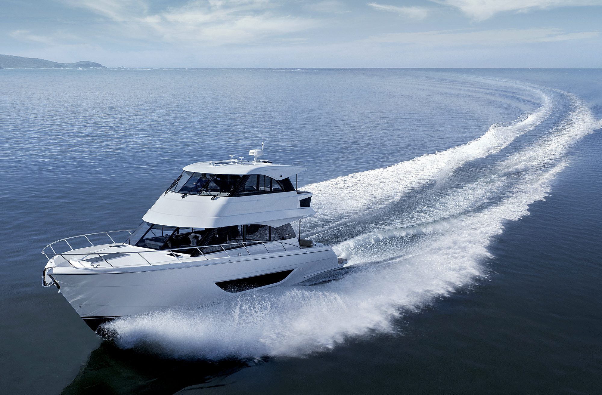 A white Maritimo M50 motor yacht cruising at high speed, carving a wide white wake across deep blue open water.
