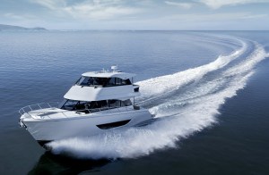A white Maritimo M50 motor yacht cruising at high speed, carving a wide white wake across deep blue open water.